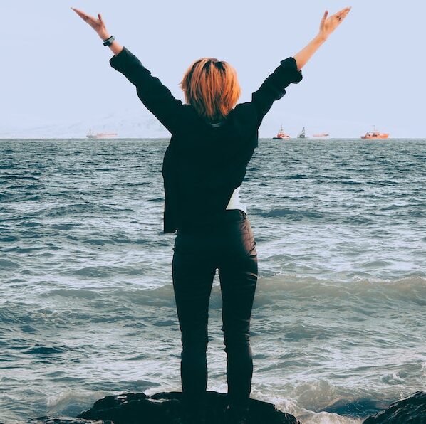 woman at ocean with arms in the air